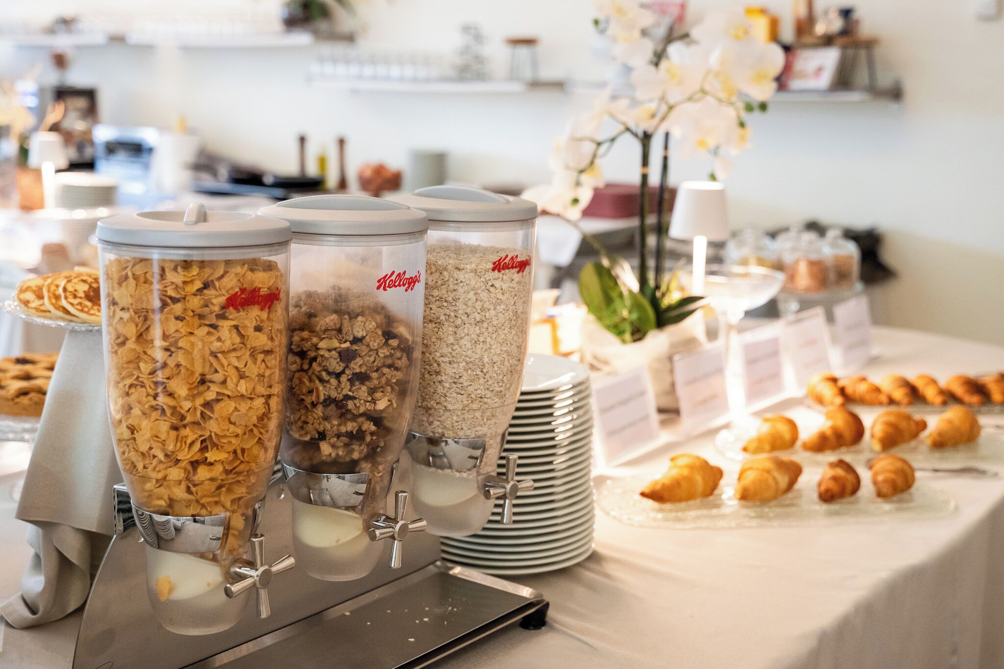 A buffet with various food options, including cereal and pastries.