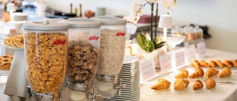 A buffet with various food options, including cereal and pastries.