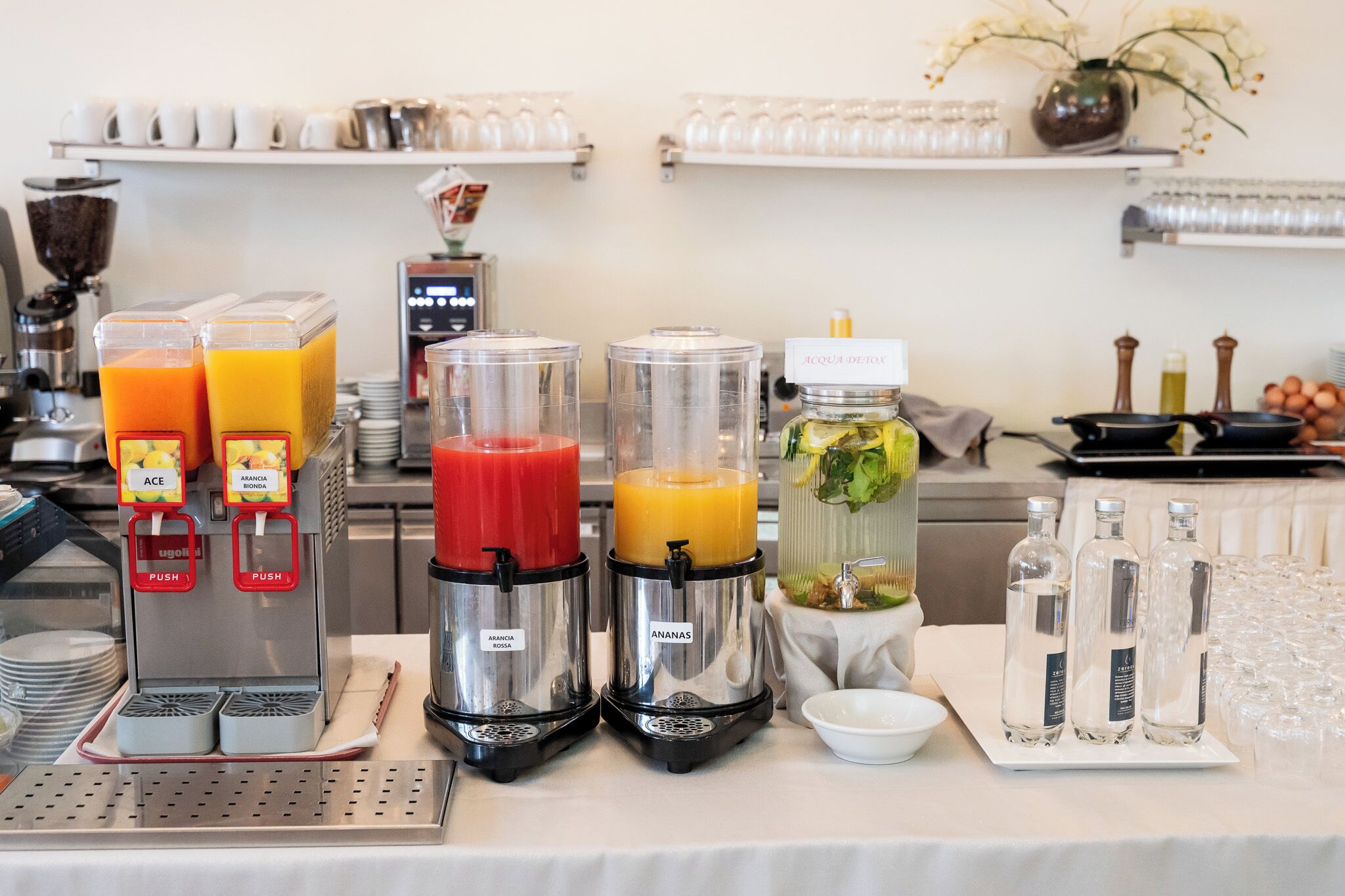 Montaje de un bufé de desayuno con dispensadores de jugo, una barra de ensaladas y una variedad de vasos.