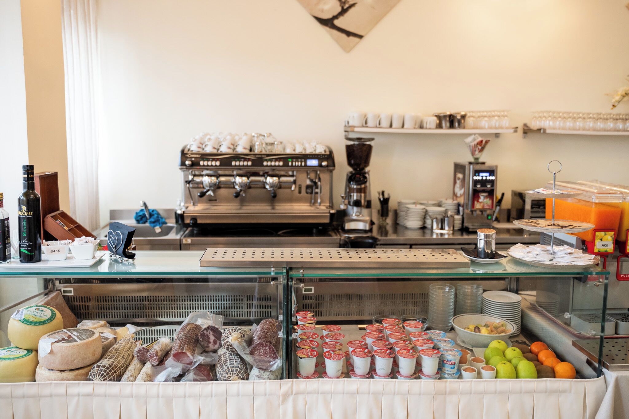 A breakfast buffet with various food items, a coffee machine, and a display of dairy products.