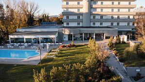 A hotel with a swimming pool, outdoor seating, and a well-maintained garden.