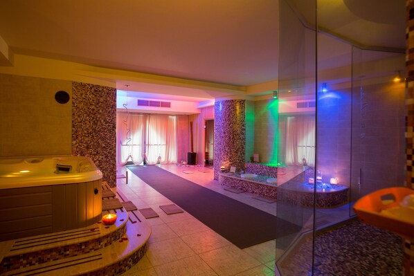 Un espace bien-être comprenant un jacuzzi, une table de massage et une douche à parois de verre.