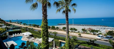 Una piscina al aire libre, sombrillas, sillones reclinables de piscina