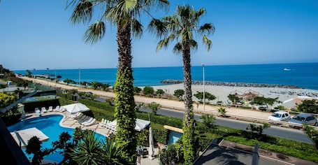 Una piscina al aire libre, sombrillas, sillones reclinables de piscina