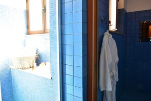 A bathroom with blue tiles, a white towel hanging on the wall, and a window providing natural light.