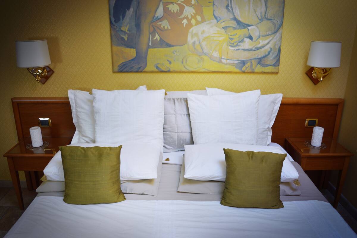A hotel room with a large bed, two nightstands, and a painting on the wall.