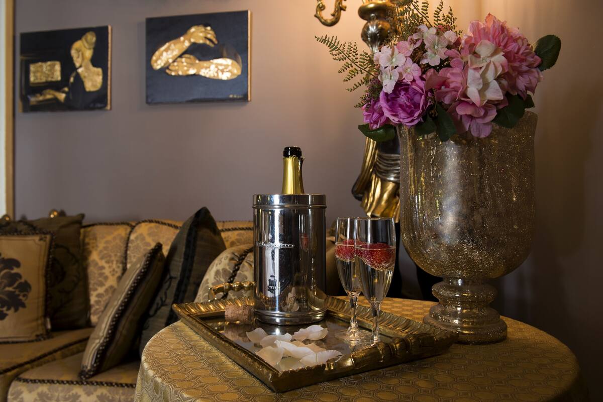 A table with a champagne bottle, glasses, and a decorative vase with flowers.
