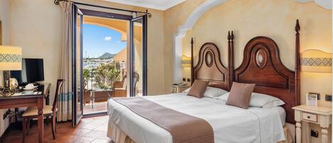 Habitación de hotel con una cama grande, un escritorio con ordenador y vistas al exterior.