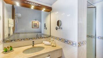 A bathroom with a sink, mirror, and shower.