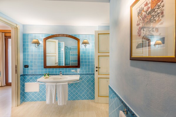 Un baño con lavamanos, espejo y dos lámparas en la pared.