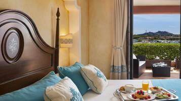 A hotel room with a bed, breakfast tray, and a view of a landscape.