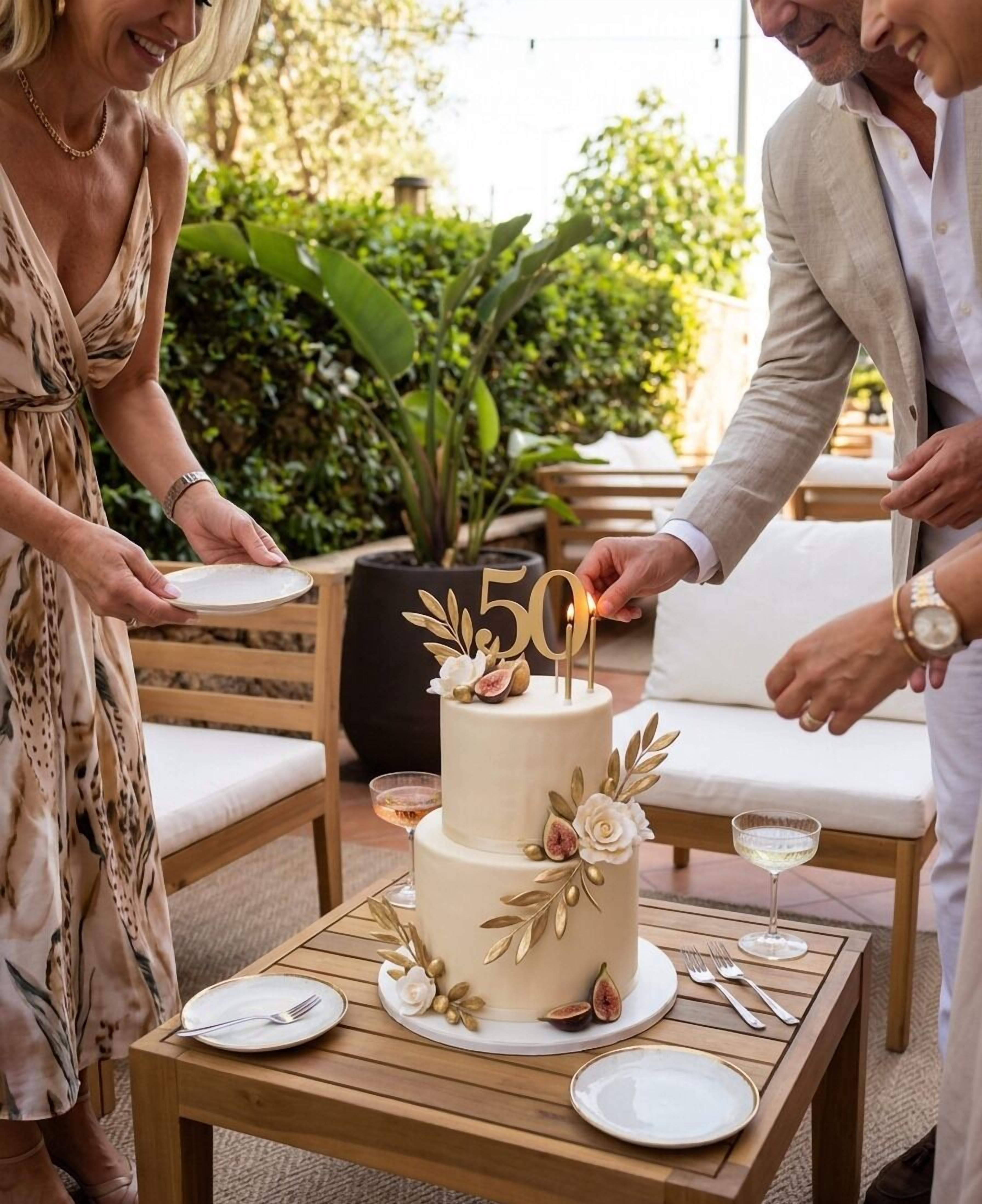 A two-tiered cake with a '50' topper, surrounded by guests.