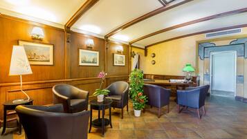 A lobby with wooden paneling, a reception desk, and several seating areas with chairs and tables.
