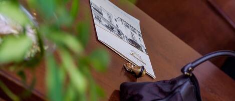 A wooden table with a black handbag, a brochure, and a pair of shoes.