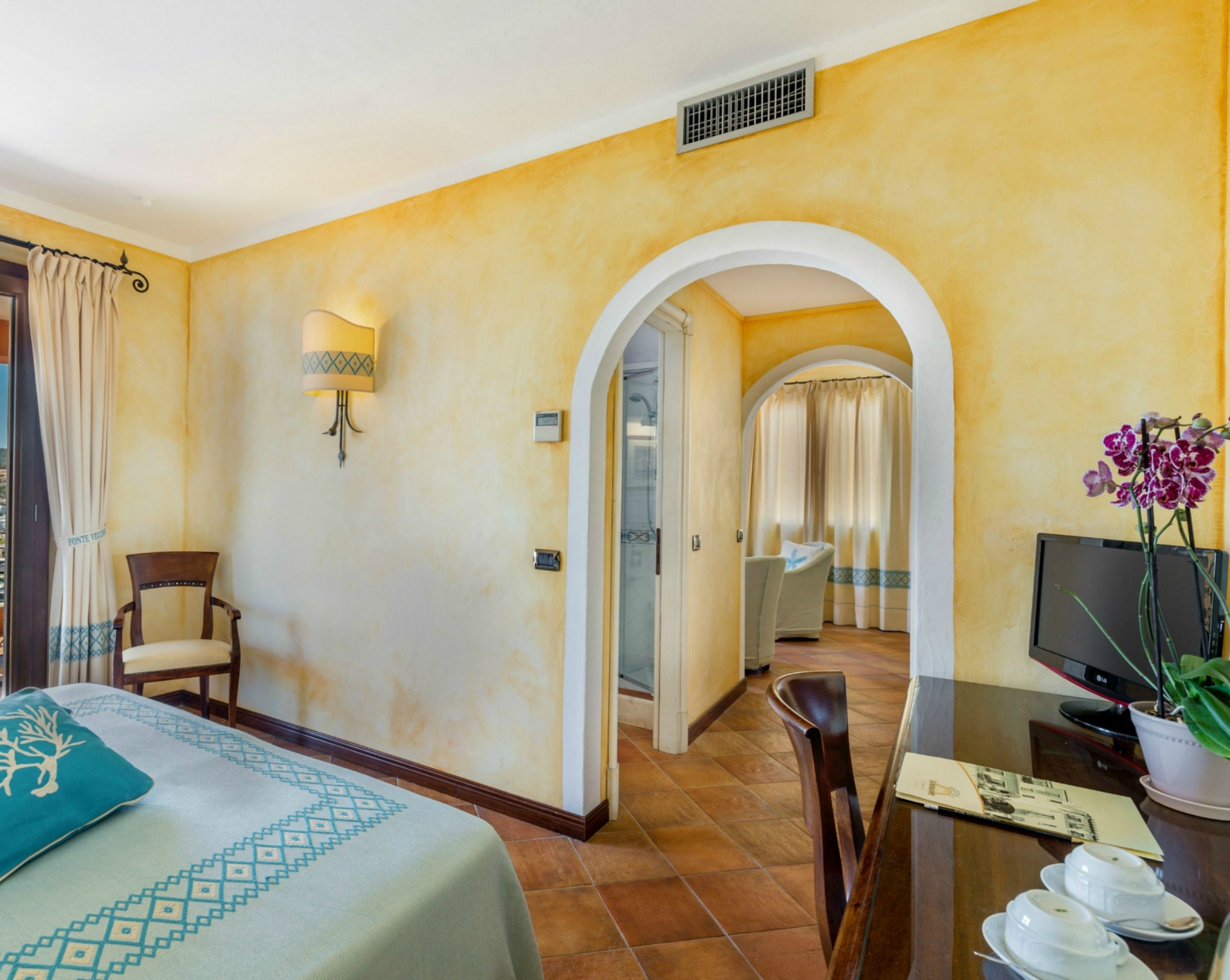 Une chambre d’hôtel avec un lit, un bureau avec un ordinateur, une chaise et un téléviseur.
