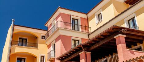 A multi-story building with balconies and a clear blue sky.