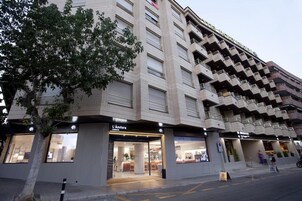 Un hotel de varios pisos con fachada moderna, que cuenta con balcones en los pisos superiores.