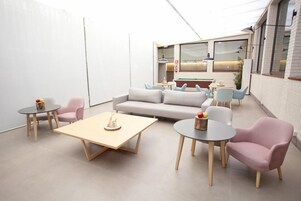 Un espacio habitable moderno y de planta abierta con un sofá, dos mesas redondas y una mesa de centro.