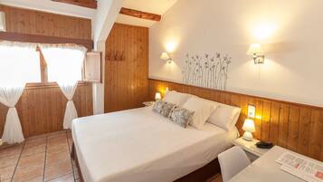 Un dormitorio con una cama grande, paredes de madera, una ventana con cortinas y dos lámparas fijadas a la pared.
