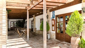 An outdoor patio area with wooden furniture, potted plants, and a stone floor. - Delta Hotel (Deltebre)