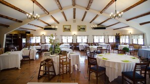 A dining area with multiple tables, wooden beams on the ceiling, and chandeliers. - Delta Hotel (Deltebre)