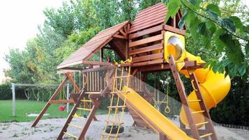 Explore the garden's play structure, featuring a slide, climbing elements, and a cozy playhouse.
