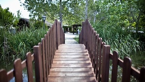A wooden bridge with railings leading to a gazebo in a park. - Delta Hotel (Deltebre)
