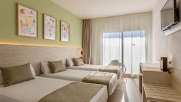 Habitación de hotel con dos camas, un escritorio, un televisor y obras de arte en la pared.
