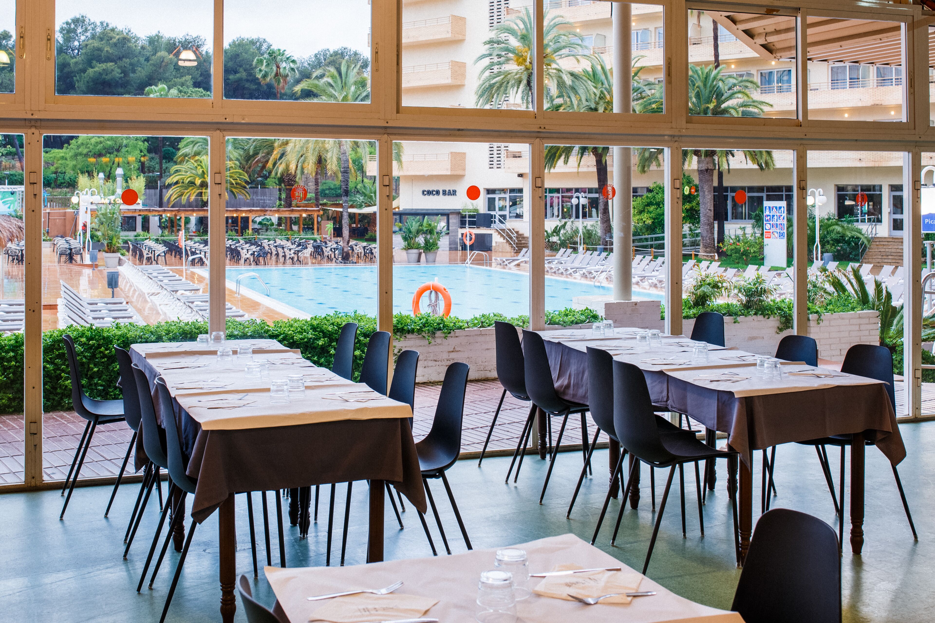 A restaurant with outdoor seating overlooking a pool and a bar.
