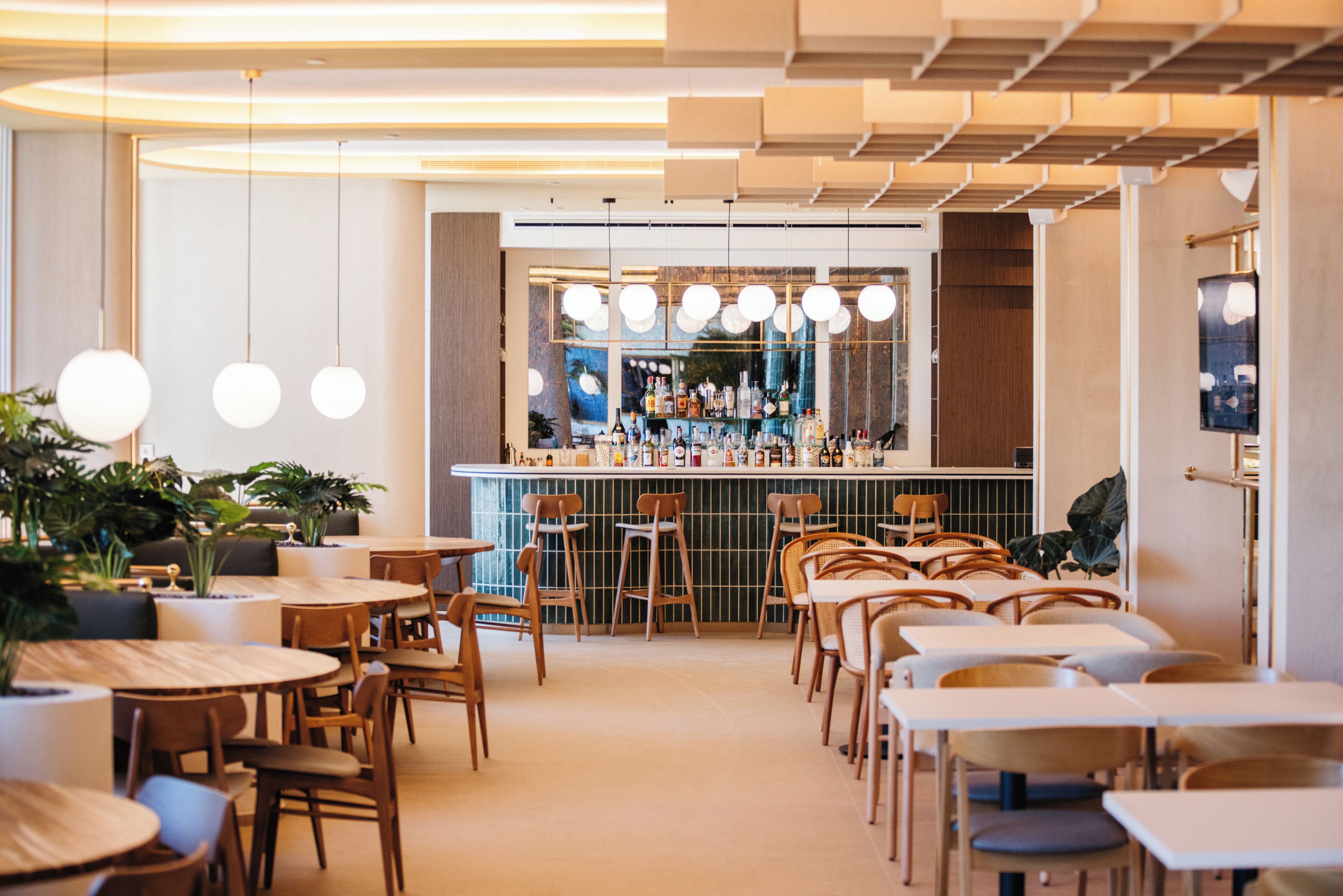 Uma área de bar moderna com balcão, bancos e luminárias esféricas penduradas.