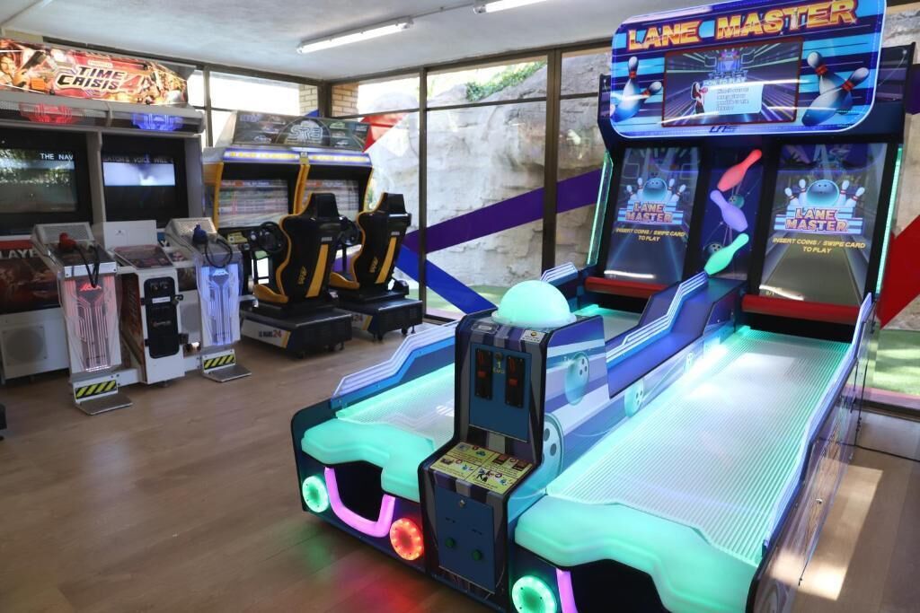 Un salón recreativo con diversas máquinas, incluyendo juegos de bolos 'Lane Master'.