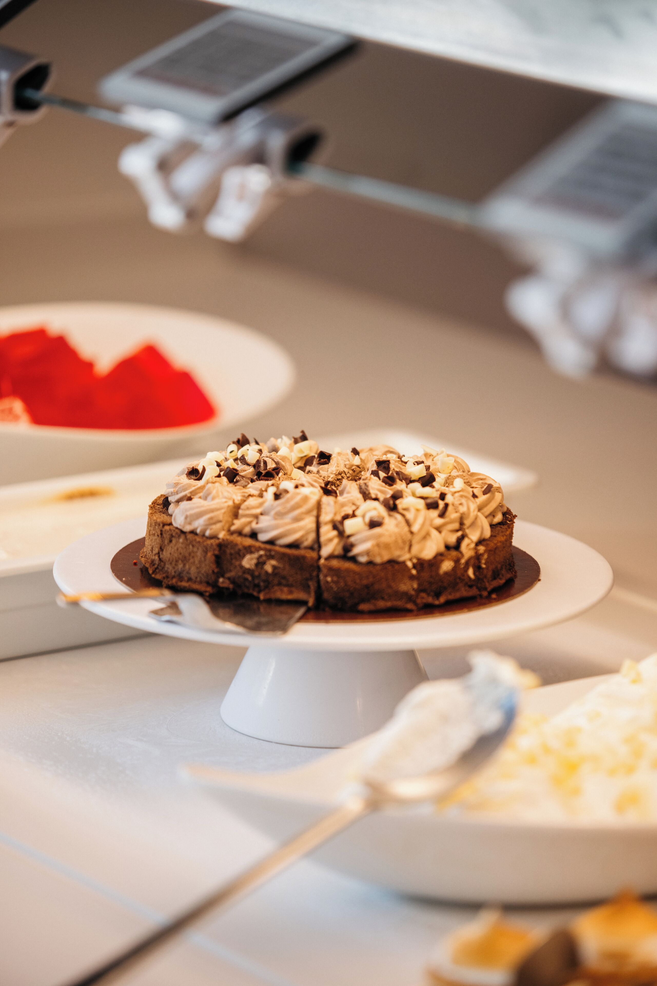 Una presentación de postres con un pastel de chocolate cubierto de crema batida y nueces, rodeado de otros dulces.