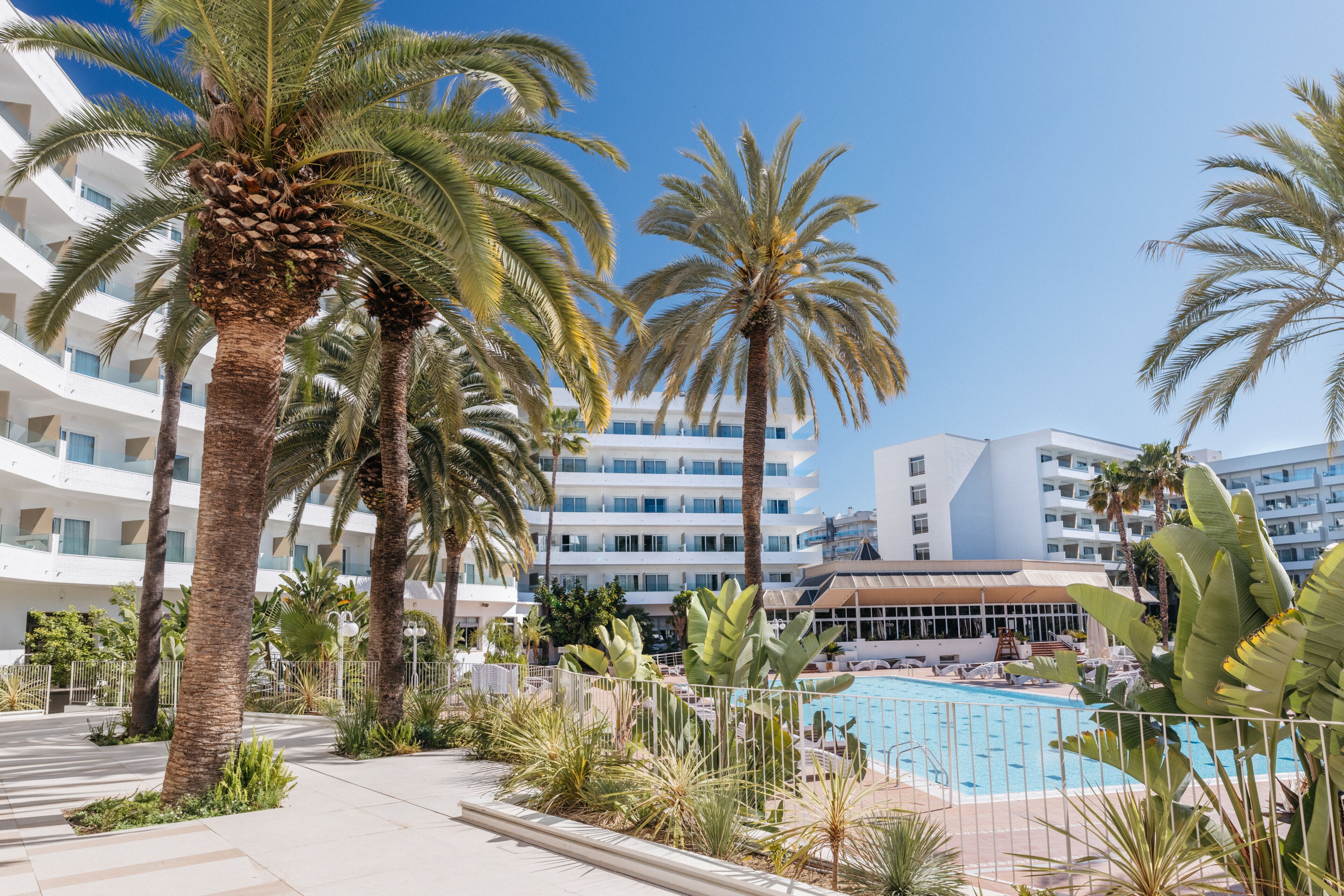 Un resort con piscina, palmeras y edificios modernos.
