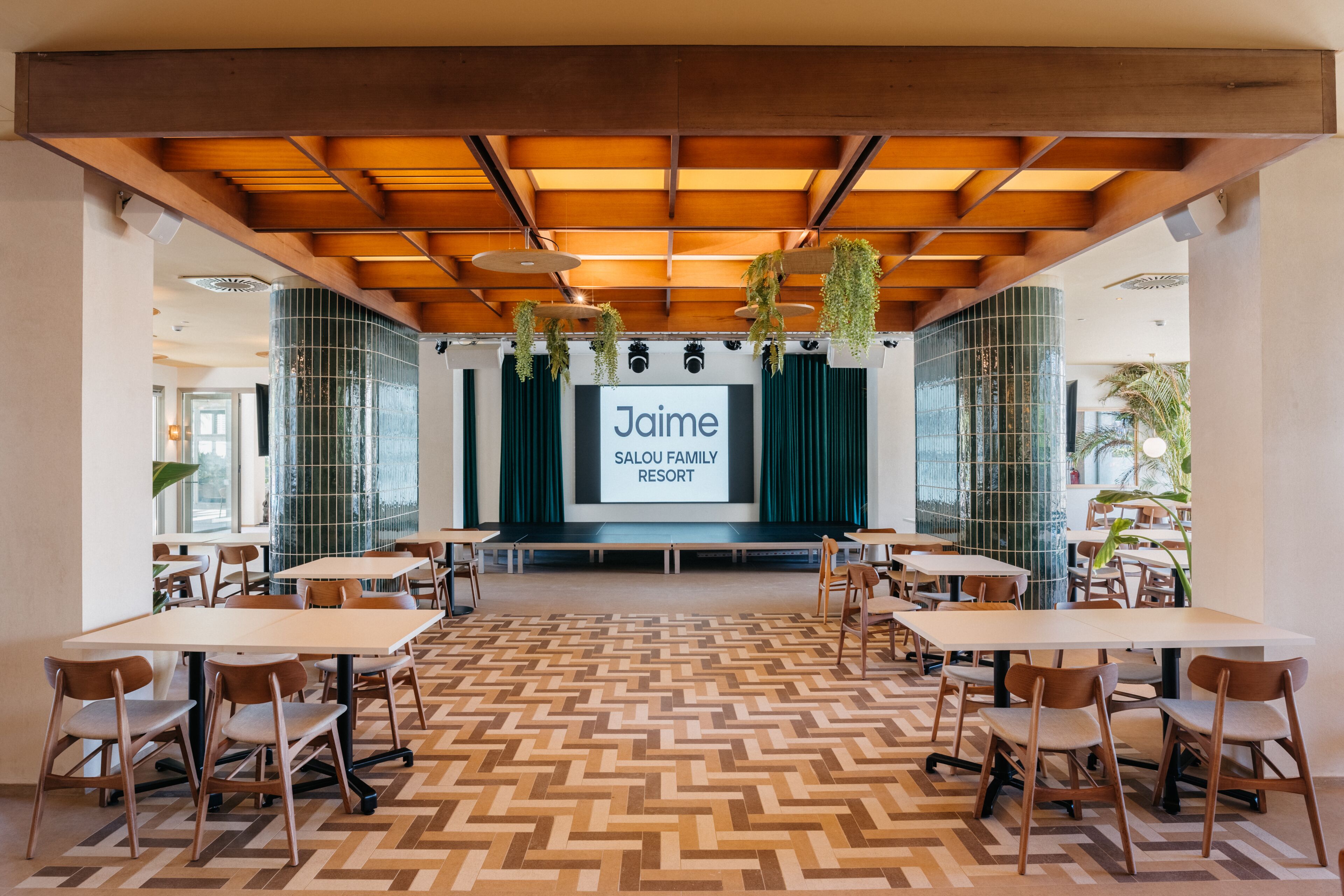 Ein Konferenzraum mit einer großen Leinwand, auf der 'Jaime SALOU FAMILY RESORT' angezeigt wird.