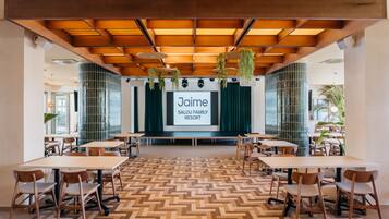 Un salón de conferencias con una pantalla grande que muestra 'Jaime SALOU FAMILY RESORT' al frente.