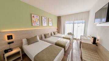 Una habitación de hotel con dos camas, un escritorio, un televisor y obras de arte en la pared.