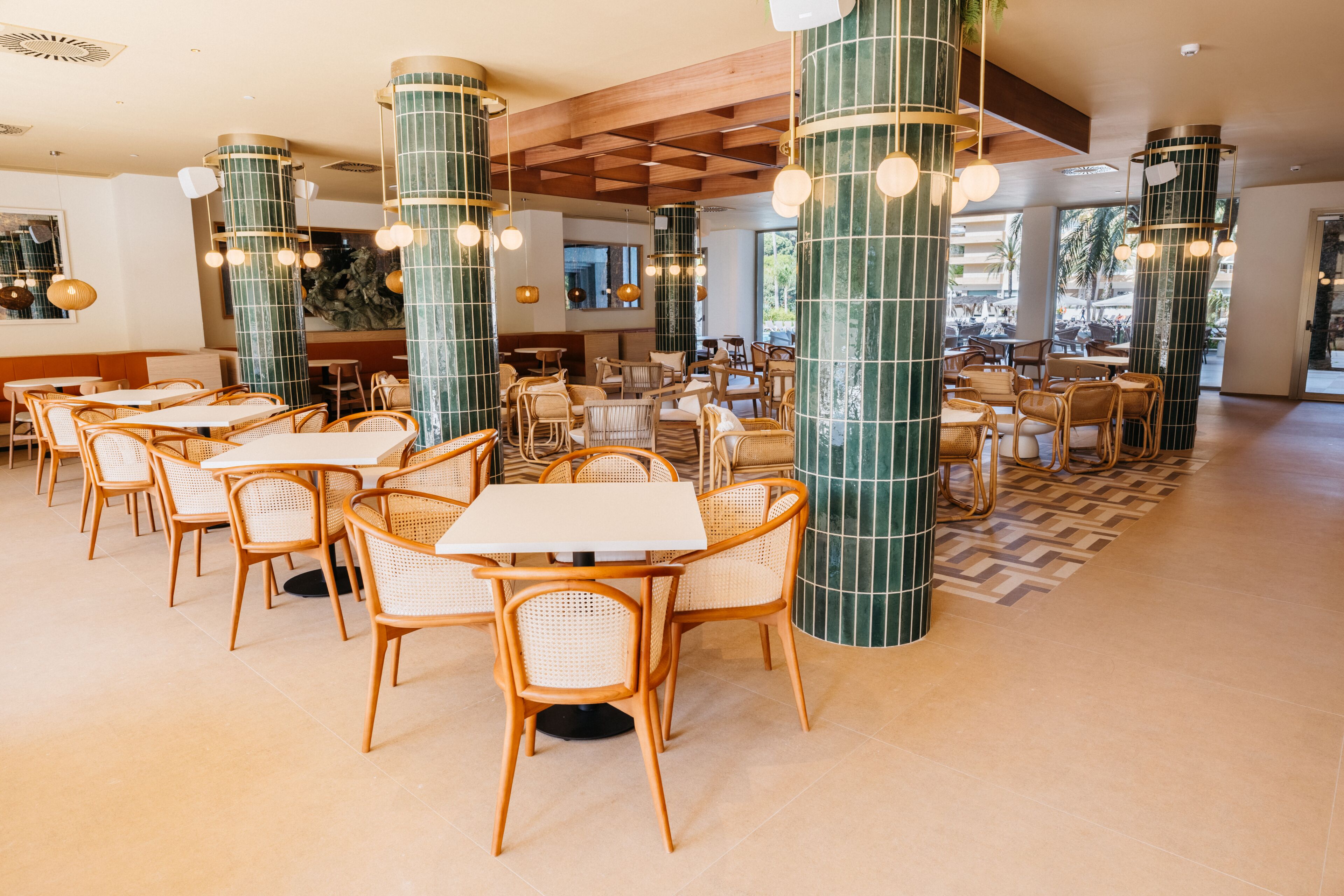 Un vaste espace intérieur aménagé avec différents types de sièges, notamment des tables et des chaises, ainsi que de grandes colonnes décoratives.