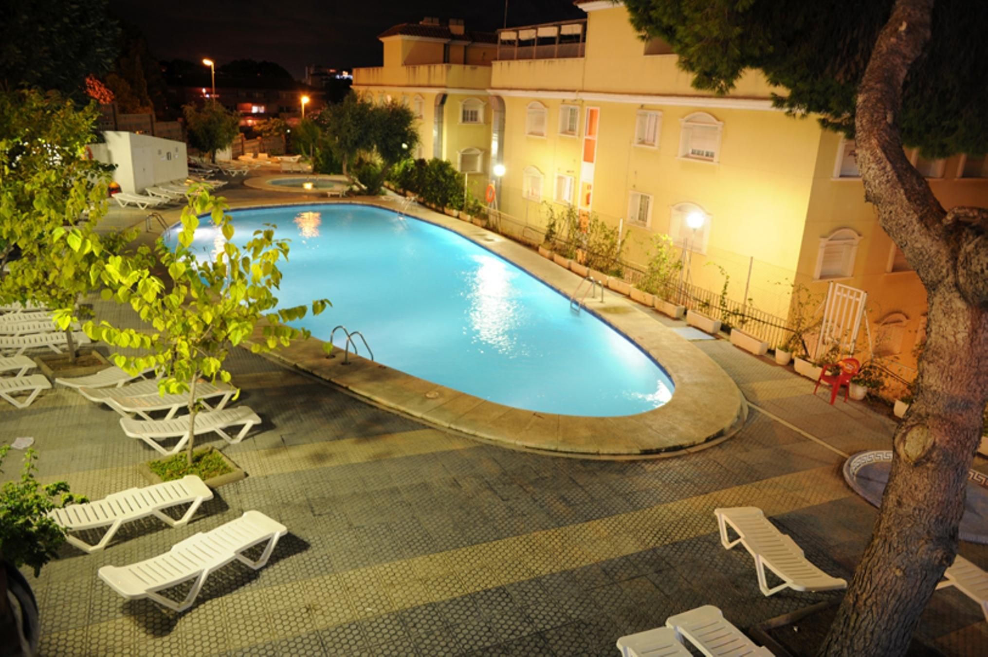 A swimming pool with lounge chairs and a paved deck area.