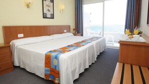 A hotel room with a large bed, a desk with a tray of breakfast, a chair, and a balcony with a view. - Natura Park (El Vendrell)