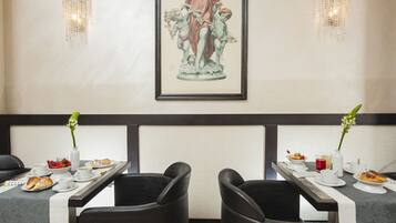 A dining area with two tables, each with a vase of flowers, plates of food, and cups.