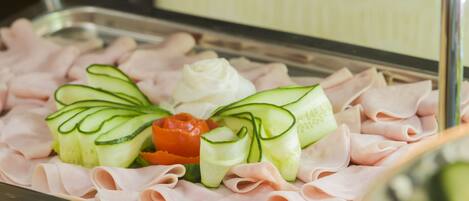 A buffet with neatly arranged sliced meats and vegetables.