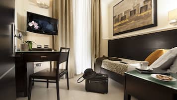 Une chambre d’hôtel équipée d’un bureau, d’une chaise, d’un lit et d’un téléviseur fixé au mur.