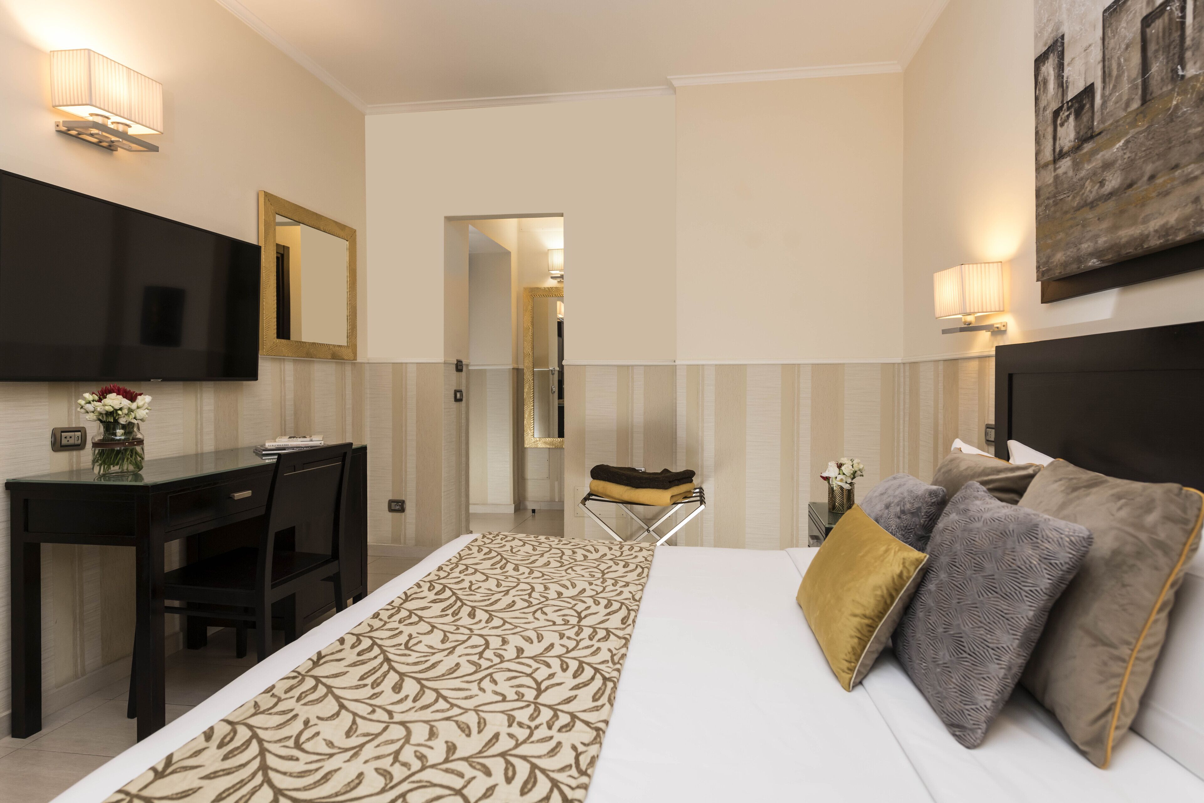 Une chambre d’hôtel avec un lit, un bureau, une chaise, une télévision et un tableau au mur.