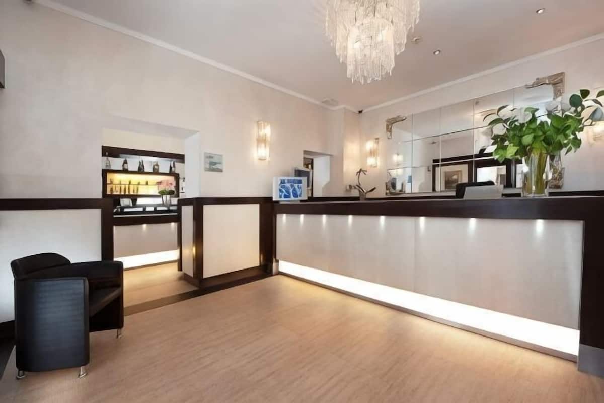 A reception area with a reception desk, seating, a chandelier, and a plant.