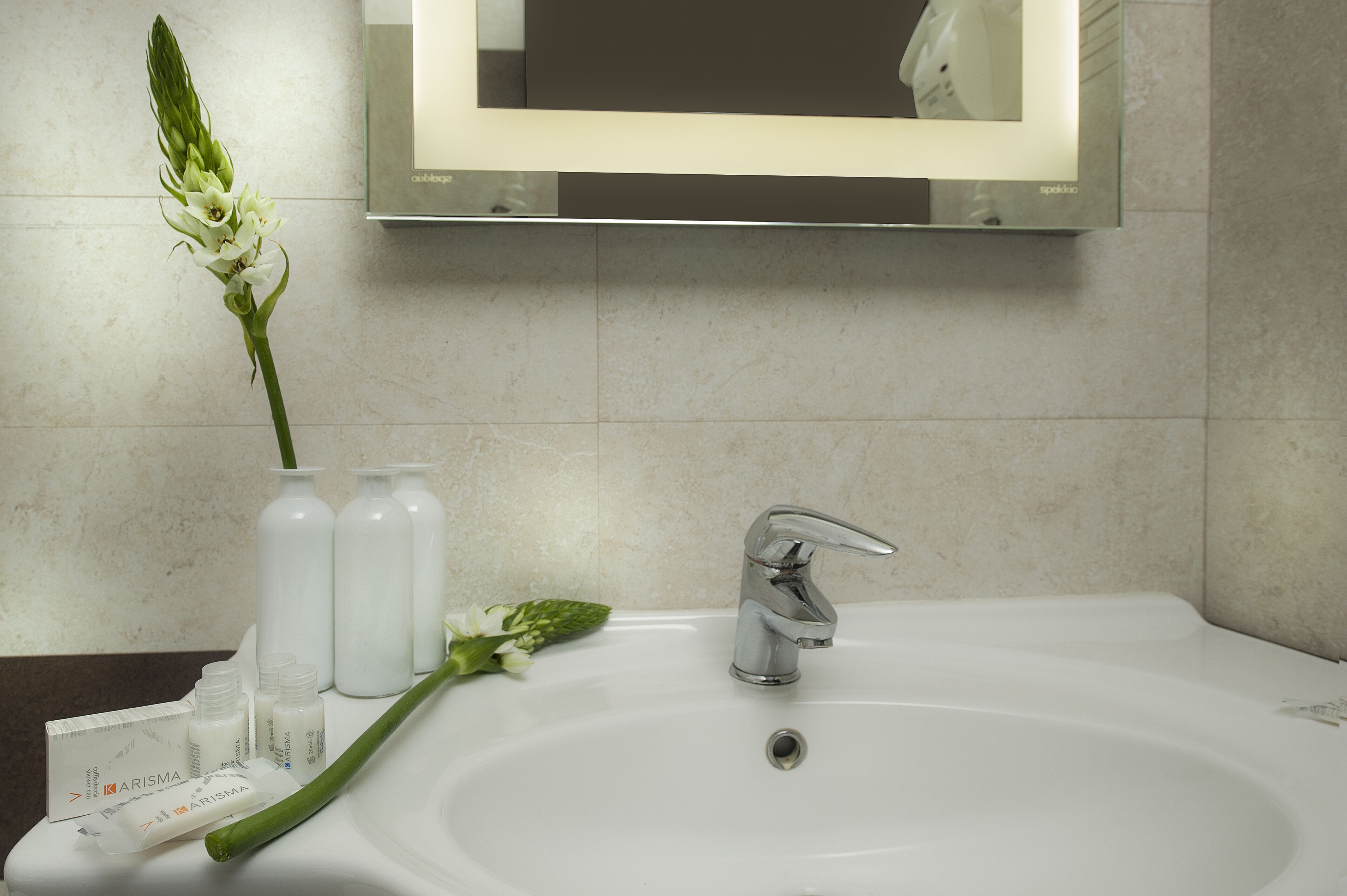 A bathroom with a white sink, a mirror, and toiletries.