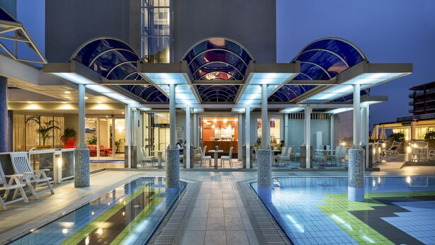 Un hôtel doté d’une piscine, d’un espace extérieur aménagé pour s’asseoir et d’une entrée couverte.