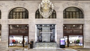Un hall imponente con una gran araña, paredes de mármol y una recepción.