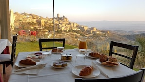 A table set for breakfast with croissants, pastries, and a pitcher of orange juice, overlooking a scenic village. - Triskel (Sos del Rey Catolico)