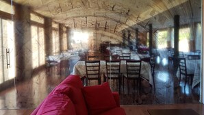 A room with a stone ceiling, a red sofa, and a table with chairs. - Triskel (Sos del Rey Catolico)