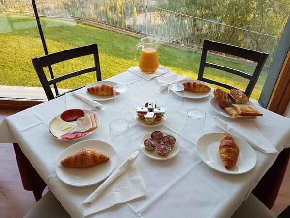 Una mesa preparada para el desayuno con croissants, bollería y una jarra de zumo de naranja.